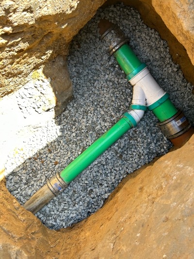 Image of a T-shaped underground pipe connection surrounded by gravel, exemplifying the quality work by DiscoverPlumbing&Rooter in San Francisco.